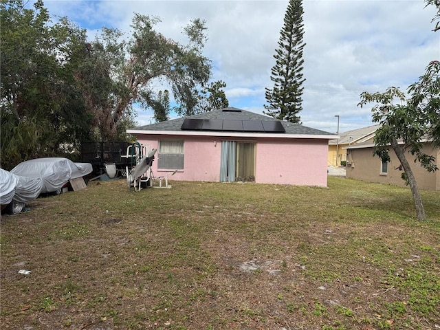 back of house with solar panels and a yard