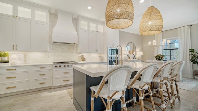 kitchen with decorative light fixtures, white cabinets, a center island, and custom range hood