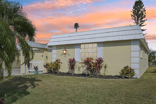 property exterior at dusk featuring a yard