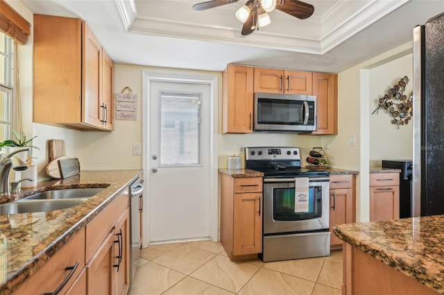 kitchen with sink, stone counters, appliances with stainless steel finishes, ornamental molding, and a raised ceiling