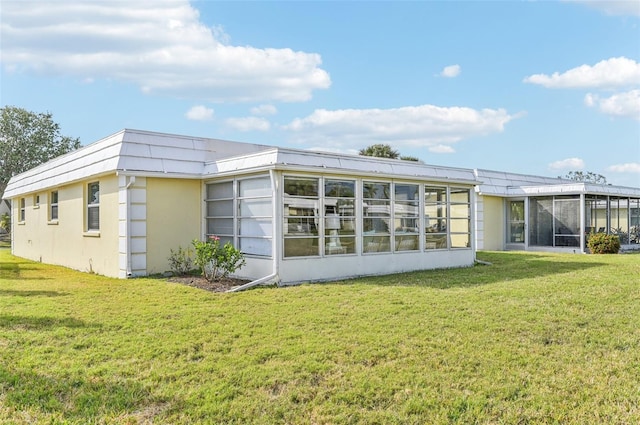 back of house featuring a sunroom and a lawn