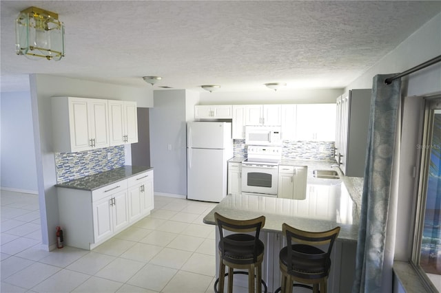 kitchen featuring white cabinetry, light tile patterned flooring, white appliances, and tasteful backsplash