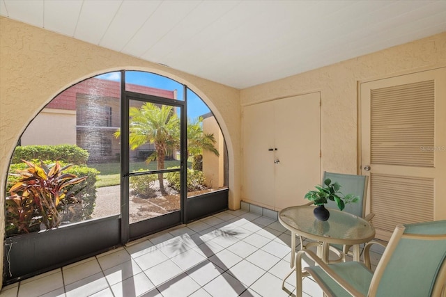 doorway with a textured wall and light tile patterned floors