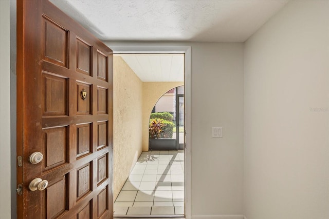 doorway featuring light tile patterned floors and a textured ceiling