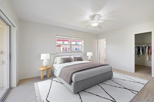 bedroom with a spacious closet, a ceiling fan, a closet, and light colored carpet