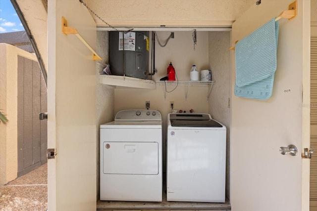 washroom featuring laundry area, water heater, and washing machine and clothes dryer