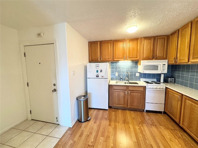 kitchen with sink, light hardwood / wood-style floors, a textured ceiling, white appliances, and decorative backsplash