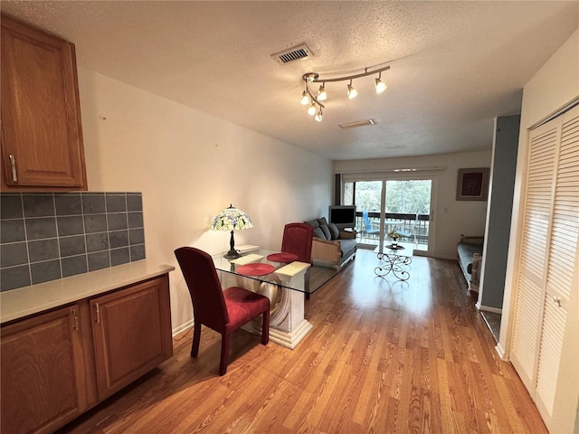 dining area featuring a textured ceiling and light hardwood / wood-style floors