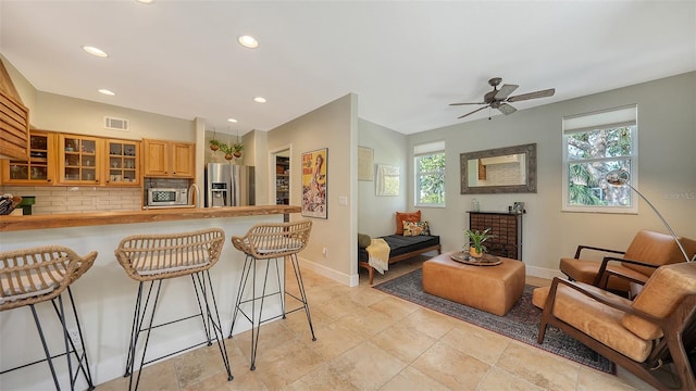 kitchen featuring a breakfast bar area, decorative backsplash, ceiling fan, and stainless steel appliances