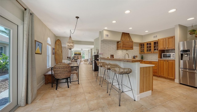 kitchen featuring tasteful backsplash, a breakfast bar, stainless steel appliances, decorative light fixtures, and a kitchen island