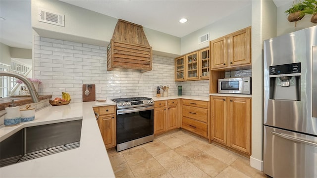 kitchen featuring decorative backsplash, stainless steel appliances, premium range hood, and sink