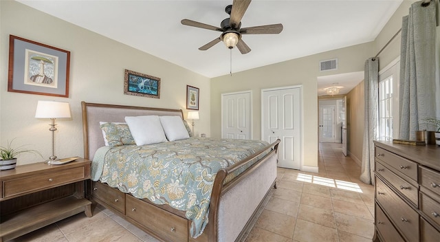 tiled bedroom with ceiling fan and multiple closets