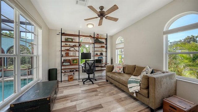 office area with light wood-type flooring, a wealth of natural light, lofted ceiling, and ceiling fan