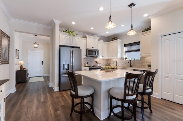 kitchen featuring crown molding, dark hardwood / wood-style flooring, stainless steel appliances, and hanging light fixtures