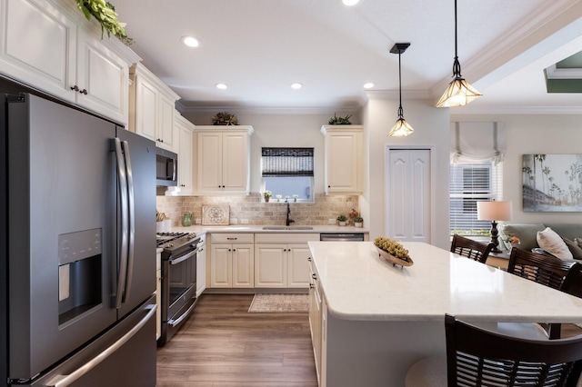 kitchen featuring stainless steel appliances, crown molding, sink, pendant lighting, and dark hardwood / wood-style floors