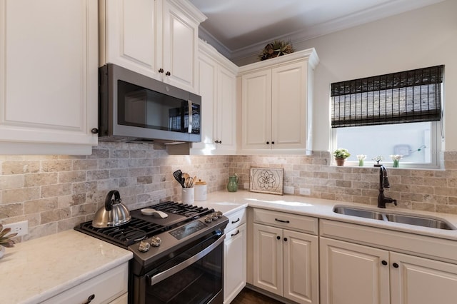 kitchen featuring white cabinets, backsplash, sink, and appliances with stainless steel finishes