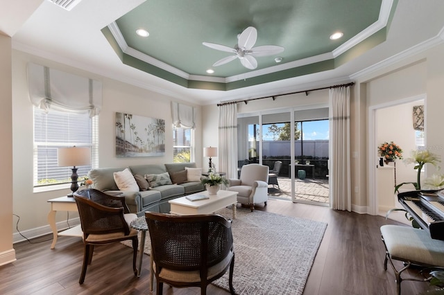 living room with ceiling fan, ornamental molding, dark wood-type flooring, and a tray ceiling