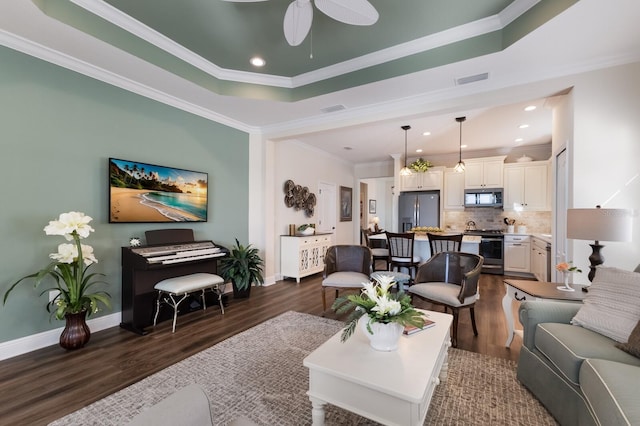 living room featuring ceiling fan, dark hardwood / wood-style flooring, crown molding, and a tray ceiling