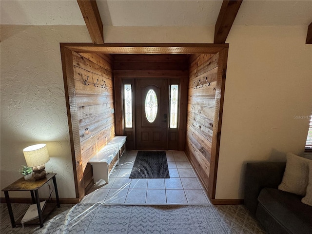 carpeted entryway featuring beam ceiling and wooden walls