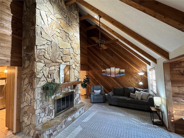 unfurnished living room featuring a fireplace, ceiling fan, high vaulted ceiling, beamed ceiling, and wood walls