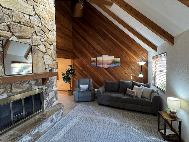 living room featuring wooden walls, high vaulted ceiling, beamed ceiling, hardwood / wood-style floors, and a stone fireplace