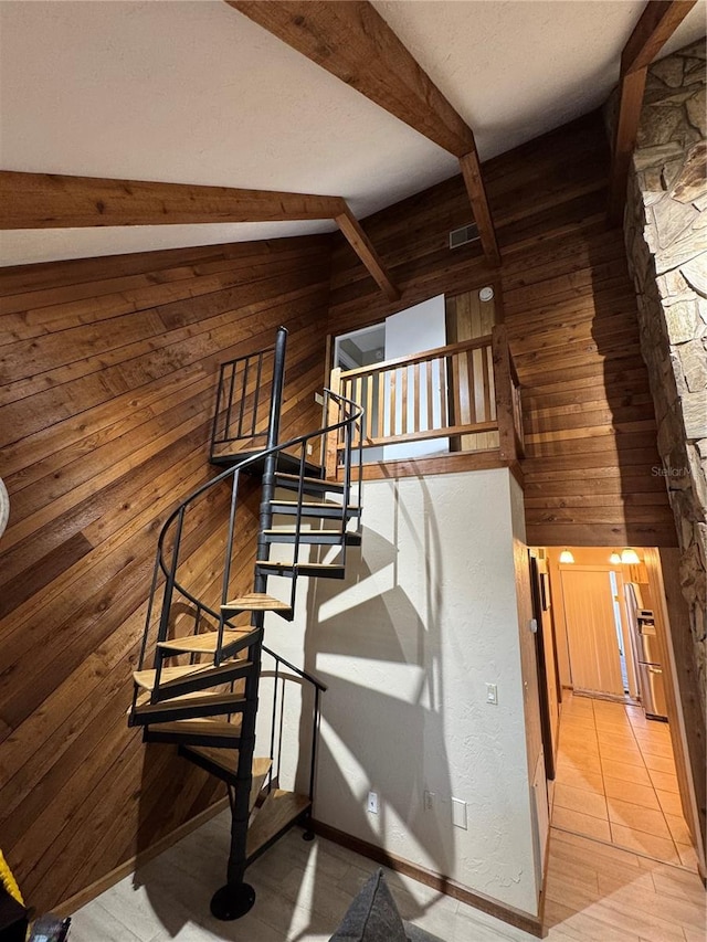 stairs with beam ceiling and wood walls