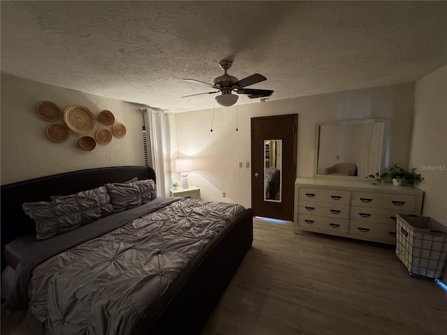 bedroom with ceiling fan, wood-type flooring, and a textured ceiling