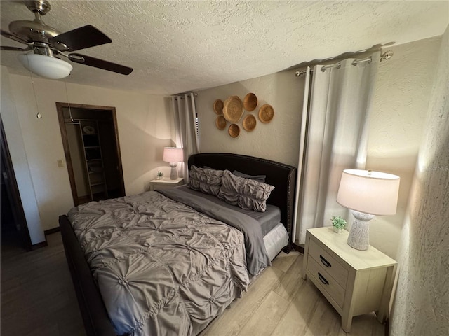 bedroom with ceiling fan, a textured ceiling, and light wood-type flooring