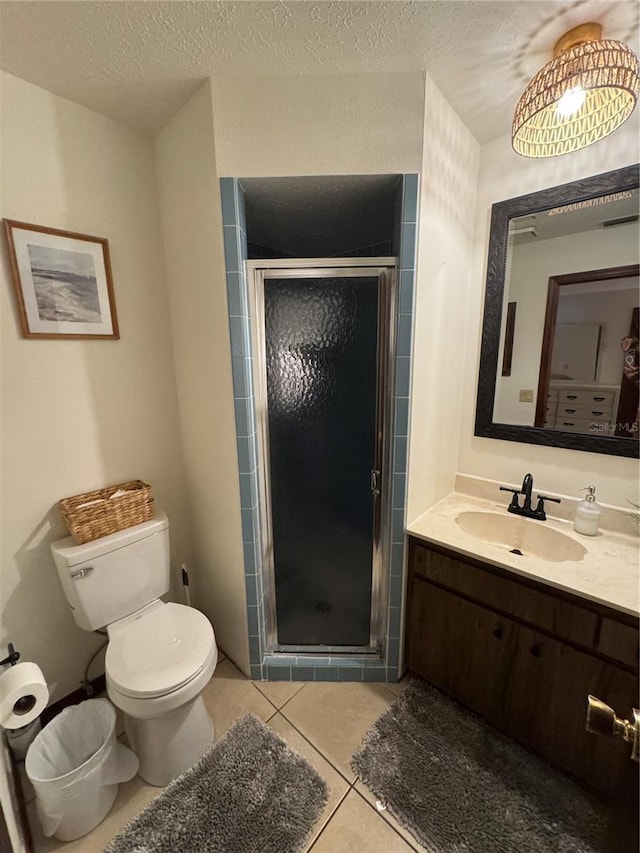 bathroom with tile patterned floors, toilet, a shower with door, and a textured ceiling