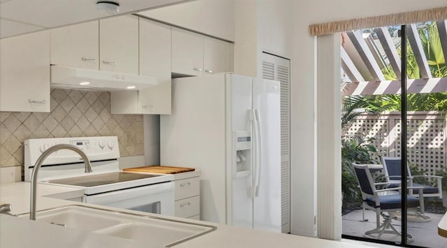 kitchen featuring sink, white appliances, white cabinetry, and backsplash