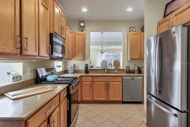 kitchen featuring appliances with stainless steel finishes, light stone counters, sink, a notable chandelier, and light tile patterned flooring