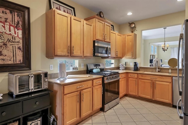 kitchen featuring appliances with stainless steel finishes, crown molding, sink, pendant lighting, and a notable chandelier