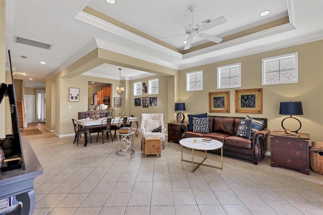 living room with ceiling fan with notable chandelier, ornamental molding, light tile patterned floors, and a tray ceiling