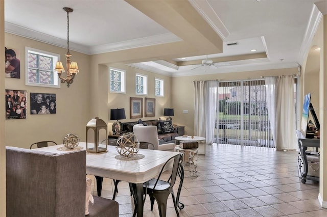 tiled dining room featuring ceiling fan with notable chandelier, a tray ceiling, and ornamental molding