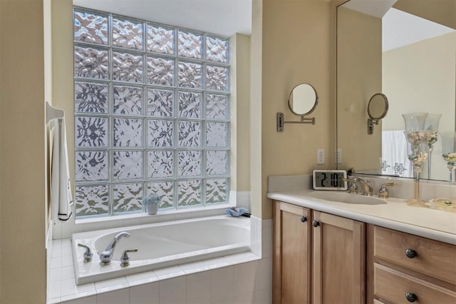 bathroom featuring tiled tub and vanity