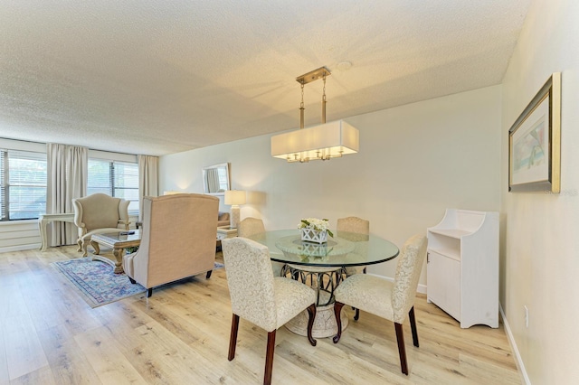 dining area with a textured ceiling and light hardwood / wood-style flooring