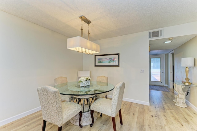 dining room featuring light hardwood / wood-style flooring and a textured ceiling