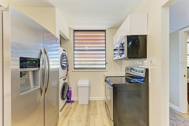 kitchen with decorative backsplash, light hardwood / wood-style floors, white cabinetry, stacked washer / dryer, and stainless steel appliances