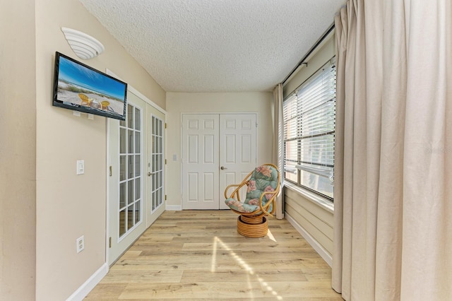 sitting room featuring a textured ceiling, light hardwood / wood-style flooring, and french doors