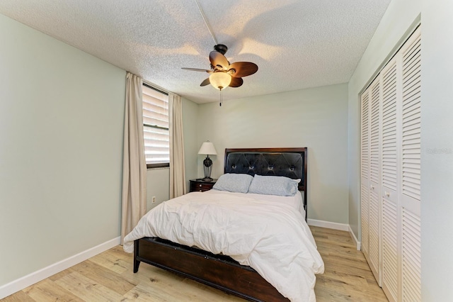 bedroom with a textured ceiling, a closet, light hardwood / wood-style flooring, and ceiling fan