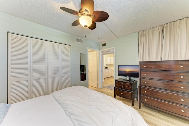 bedroom featuring ceiling fan, a closet, light hardwood / wood-style floors, and a textured ceiling