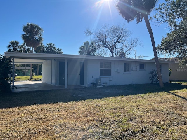 back of property with a carport and a yard