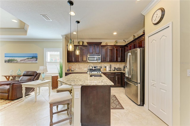 kitchen with pendant lighting, a kitchen island with sink, a breakfast bar area, light stone countertops, and stainless steel appliances