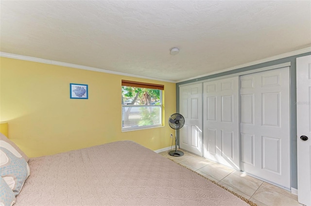 bedroom with a textured ceiling, light tile patterned floors, ornamental molding, and a closet