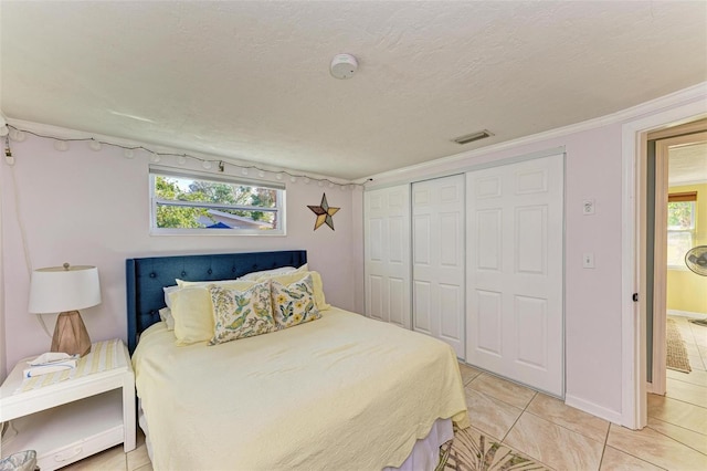 tiled bedroom with multiple windows, a closet, and ornamental molding