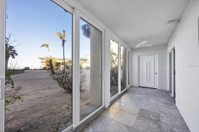 unfurnished sunroom with ceiling fan