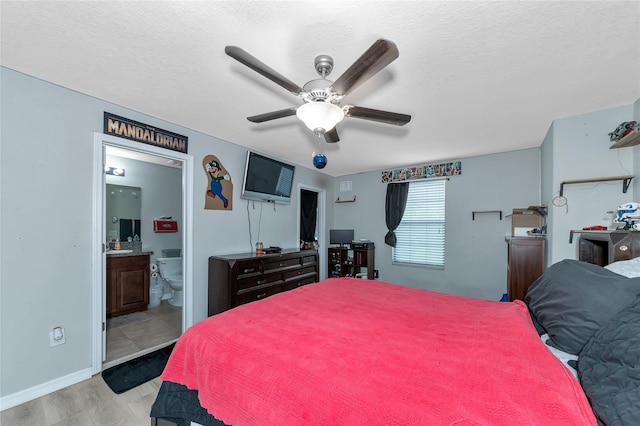 bedroom with ensuite bathroom, a textured ceiling, ceiling fan, and light wood-type flooring