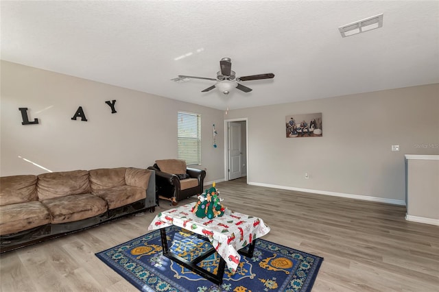 living room featuring a textured ceiling, hardwood / wood-style floors, and ceiling fan