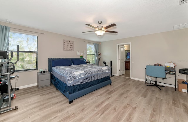 bedroom featuring ceiling fan, light hardwood / wood-style flooring, and multiple windows