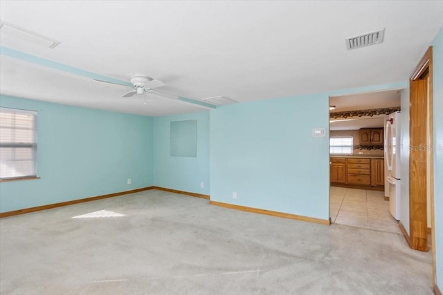 unfurnished room featuring light carpet, a wealth of natural light, and ceiling fan